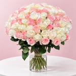 Rounded arrangement of 75 light pink and white roses in a glass vase