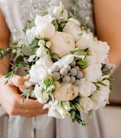 Bride holding a white wedding bouquet with greenery
