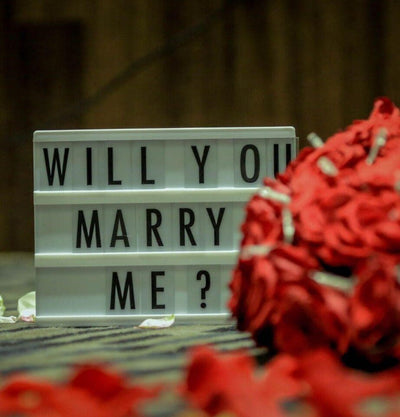 Red roses beside a Will You Marry Me sign