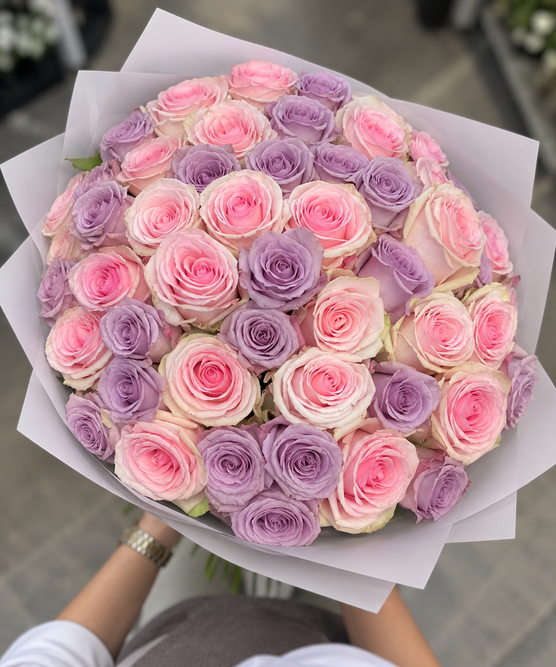 50 pink and purple roses in a round bouquet, viewed from above
