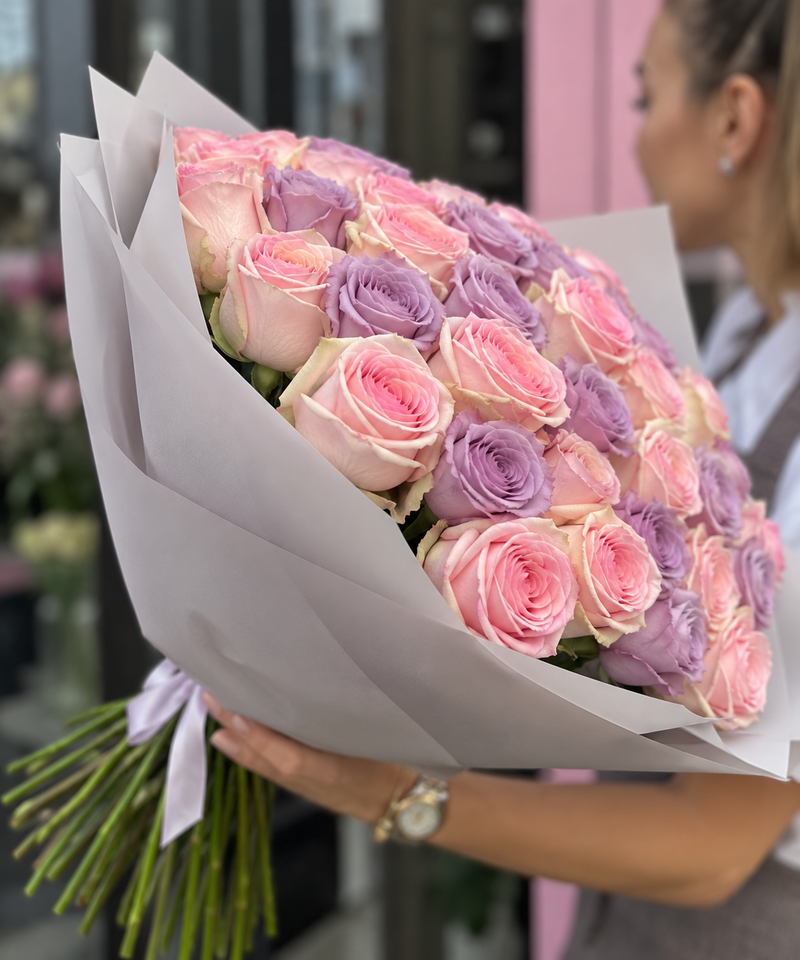 Bouquet of 50 light pink and purple roses in pale wrapping with long stems