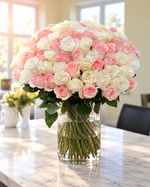 75 white and pink roses in a glass vase with green foliage